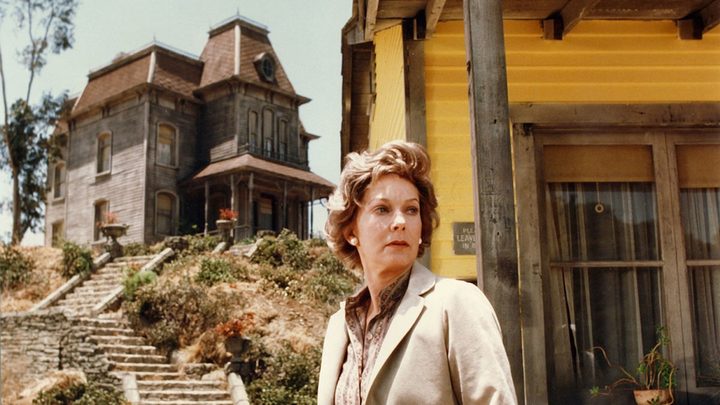 A woman stands near the Bates Motel in Psycho II.