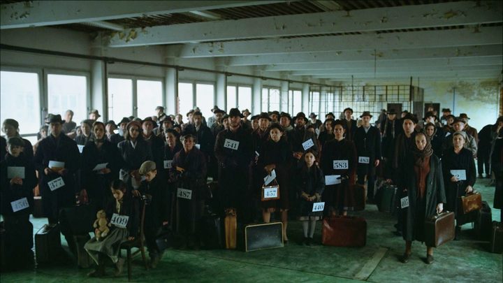 A crowd of people wait on a ferry in The Brutalist.