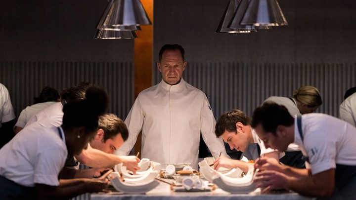 A chef stands over his staff who are meticulously putting together a dish in The Menu.