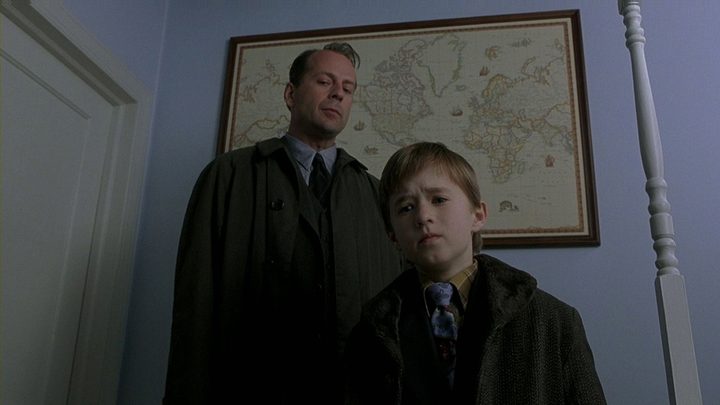 Bruce Willis stands over Haley Joel Osment in an overhead shot from The Sixth Sense.