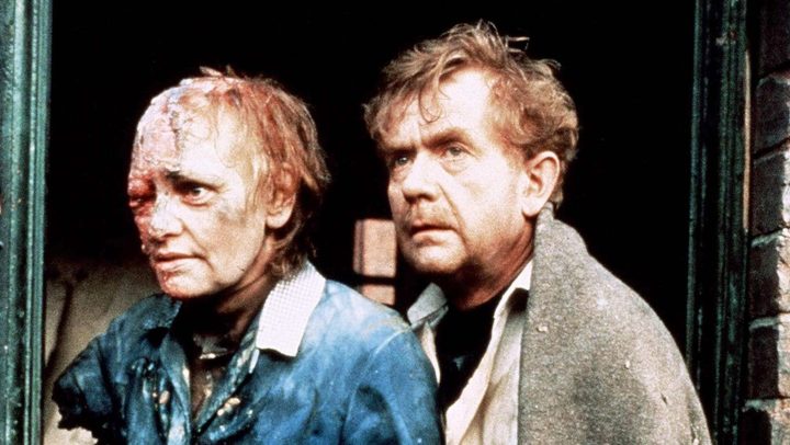 A man and a mutated woman stand in rubble in Threads.