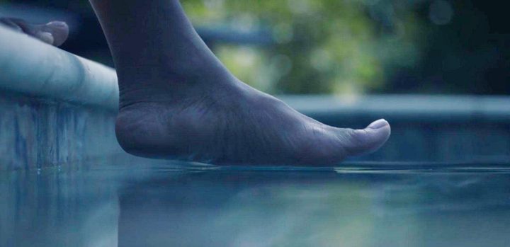 A woman places her foot in a pool in Watchmen.