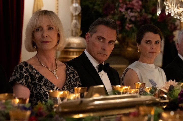 A man sits between two women at a dinner table.
