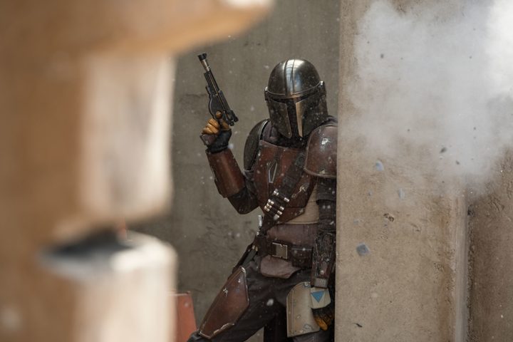Din Djarin stands behind cover in The Mandalorian.