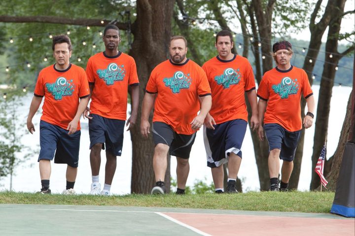 Five men walk up a hill onto a basketball court.