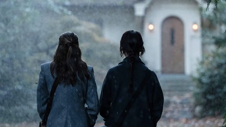 Two girls stand in front of a house in Heretic.