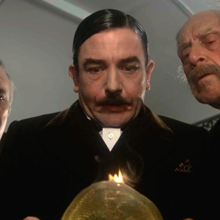 Three men looking down at a burning flame in 1974's "Murder on the Orient Express."