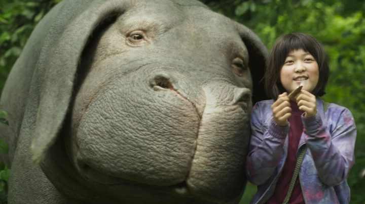 Mija smiling next to her super pig Okja.