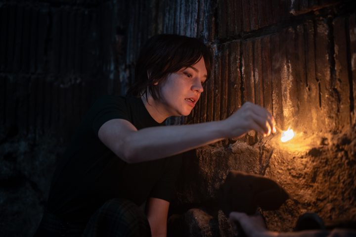 Sophie Thatcher holds a lit match in Heretic.