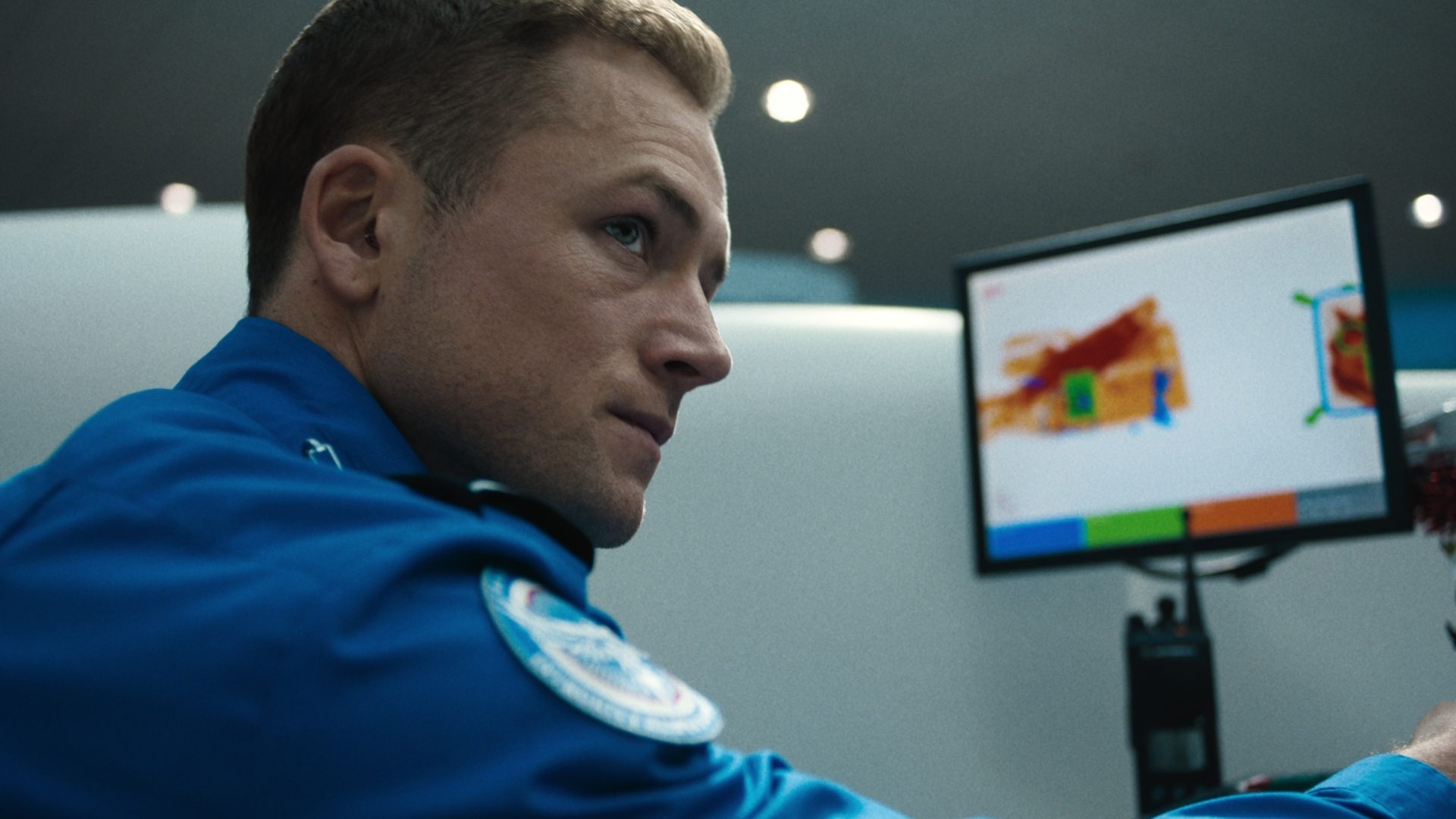 A TSA Agent looks to the right of his computer.