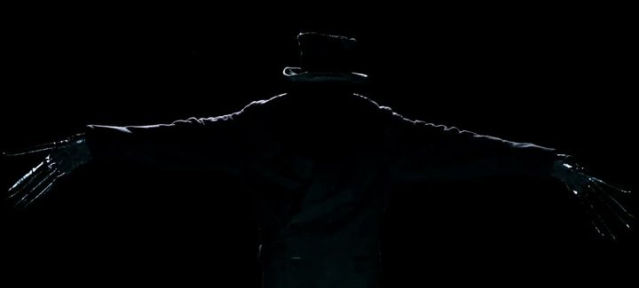 The Babadook stretches out its arms in the dark.