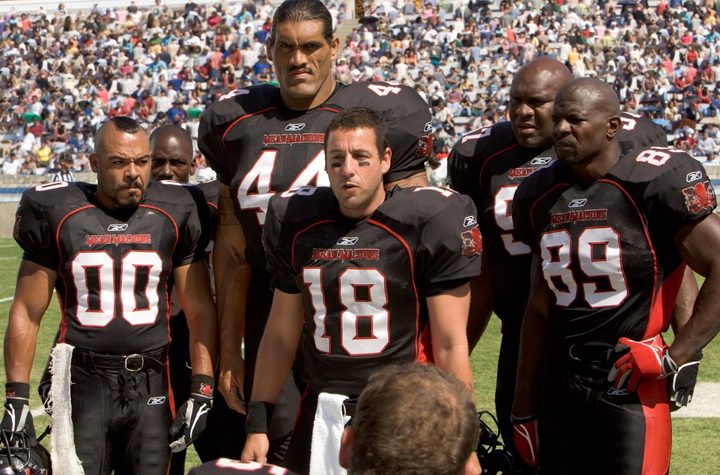 A football team stands on the sidelines and talks.
