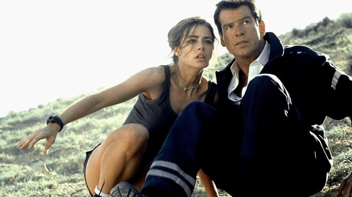 A woman sits up against a man on a rock.