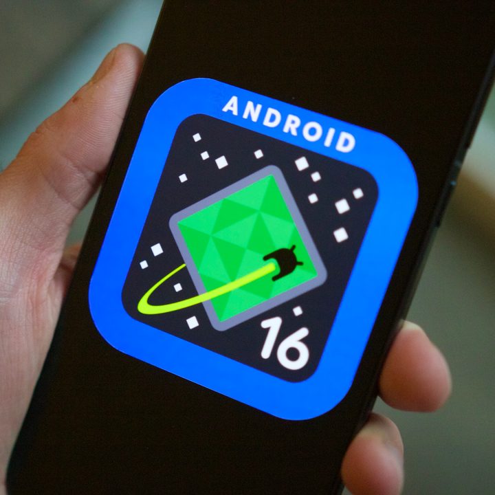 Someone holding a phone showing the Android 16 logo on its screen.