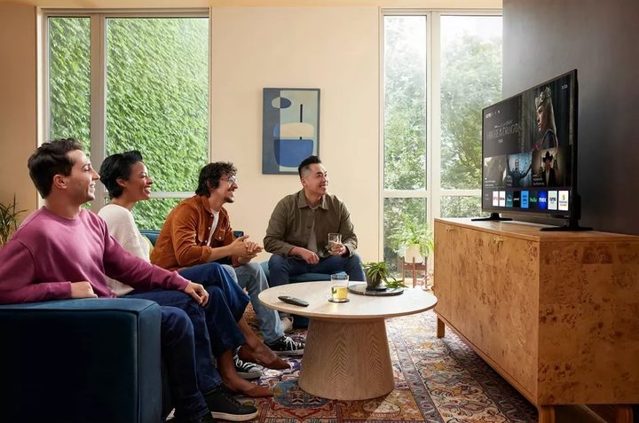 A group of people sitting on a couch watching a Xumo TV.