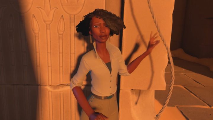 A Black woman standing in front of an Egyptian tomb about to grab a rope.