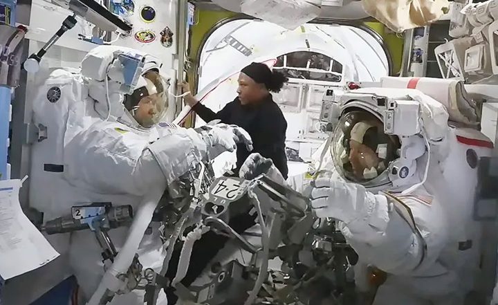 NASA astronaut Jeanette Epps (center) assists NASA astronauts Mike Barratt (left) and Tracy C. Dyson inside the Quest airlock.