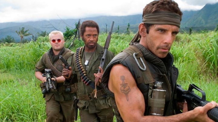 Three man led by Ben Stiller stand in the wilderness in army uniforms holding guns in Tropic Thunder.