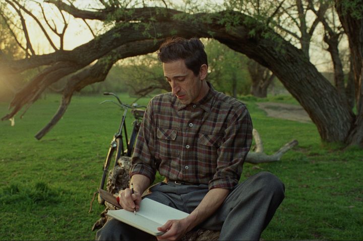 Adrien Brody sketches under a tree in The Brutalist.