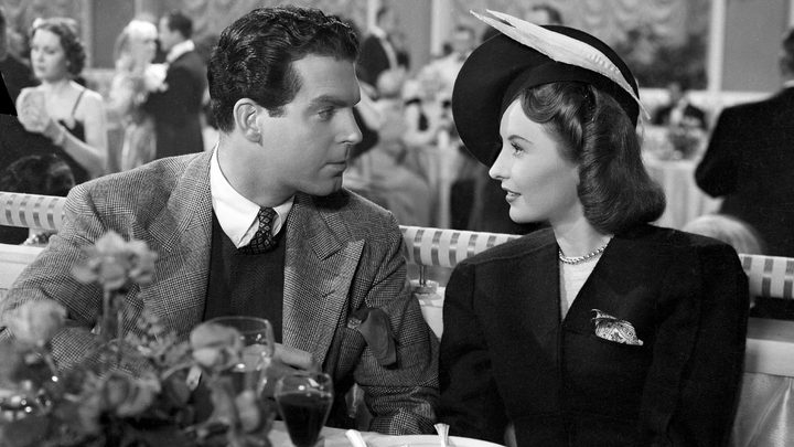 Fred MacMurray and Barbara Stanwyck as Jack and Lee looking at each other at a restaurant in Remember the Night.