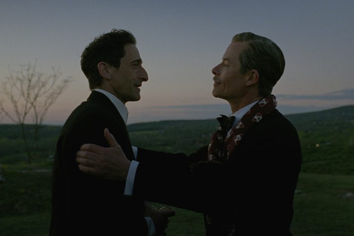 Guy Pearce grasps Adrien Brody's shoulders in The Brutalist.