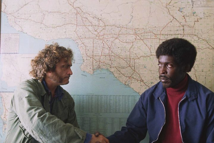Joaquin Phoenix and Michael K. Williams stand in front of a map in Inherent Vice.