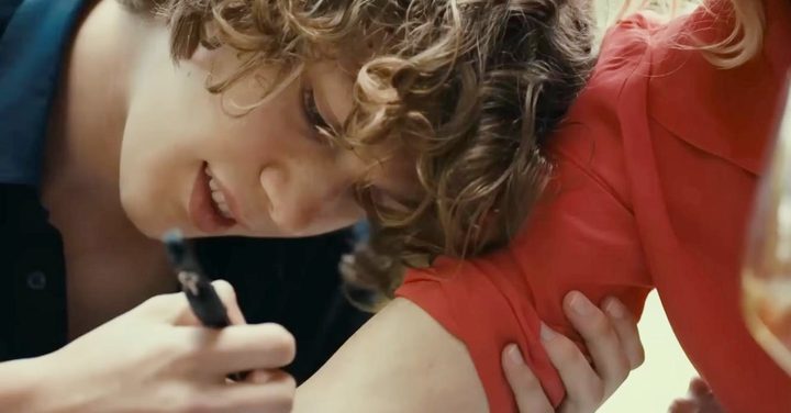 A boy writes on a woman's arm in Last Summer.