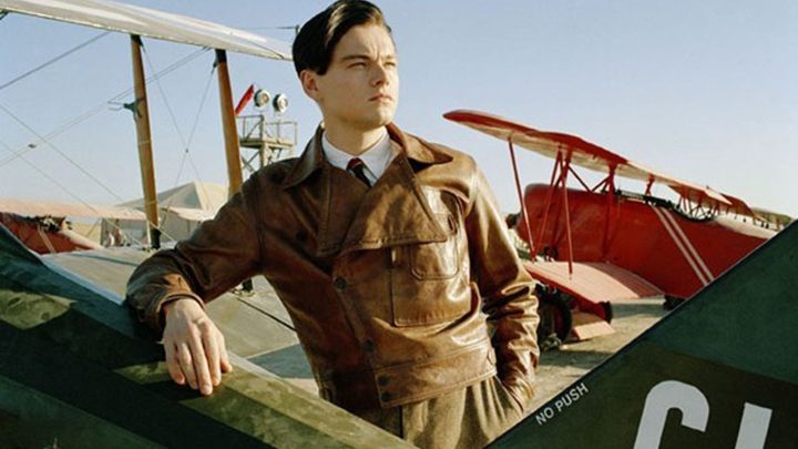 Leonardo DiCaprio as Howard Hughes posing next to a war plane in The Aviator.