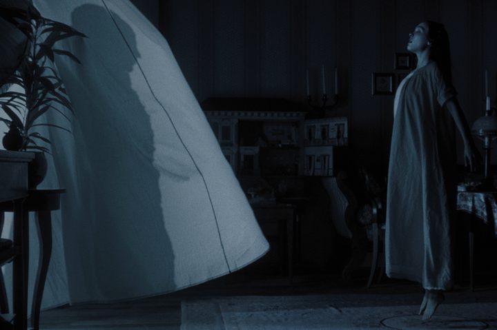 Lily-Rose Depp floats in front of billowing window curtains in "Nosferatu."