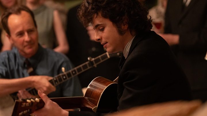 Timothee Chalamet holds a guitar and plays in A Complete Unknown.