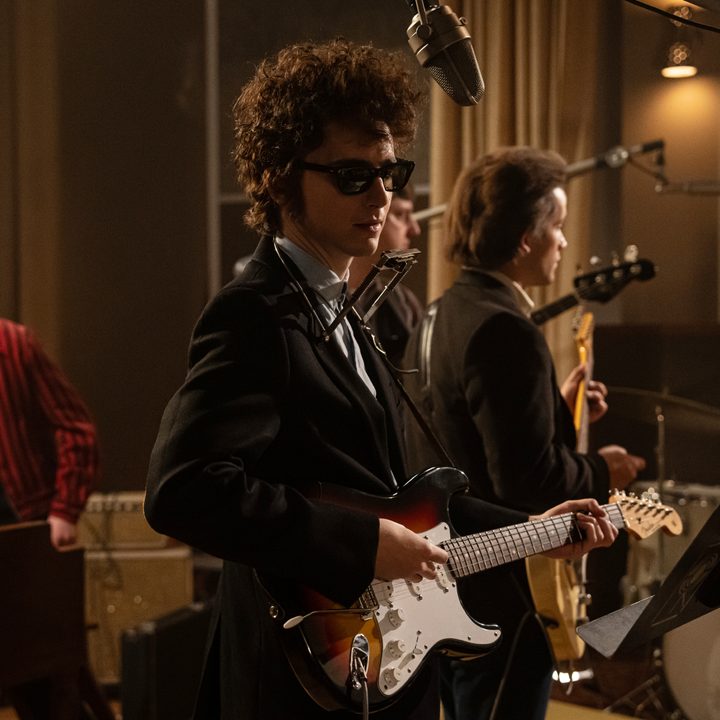 Timothée Chalamet stands in a recording studio in a still from the movie A Complete Unknown.