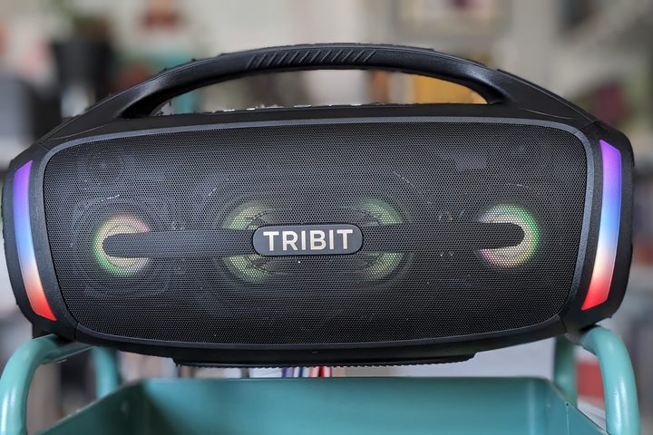 The Tribit Stormbox Blast 2 balances on a shelf, the LED lights are lit up in a rainbow pattern.