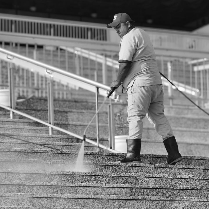 Worker cleaning stairs of a stadium with a pressure washer, captured with the Vivo X200 Pro.