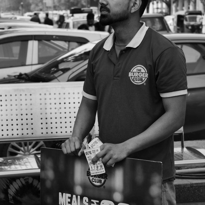 Man standing with a promotional board on street captured with Vivo X200 Pro.