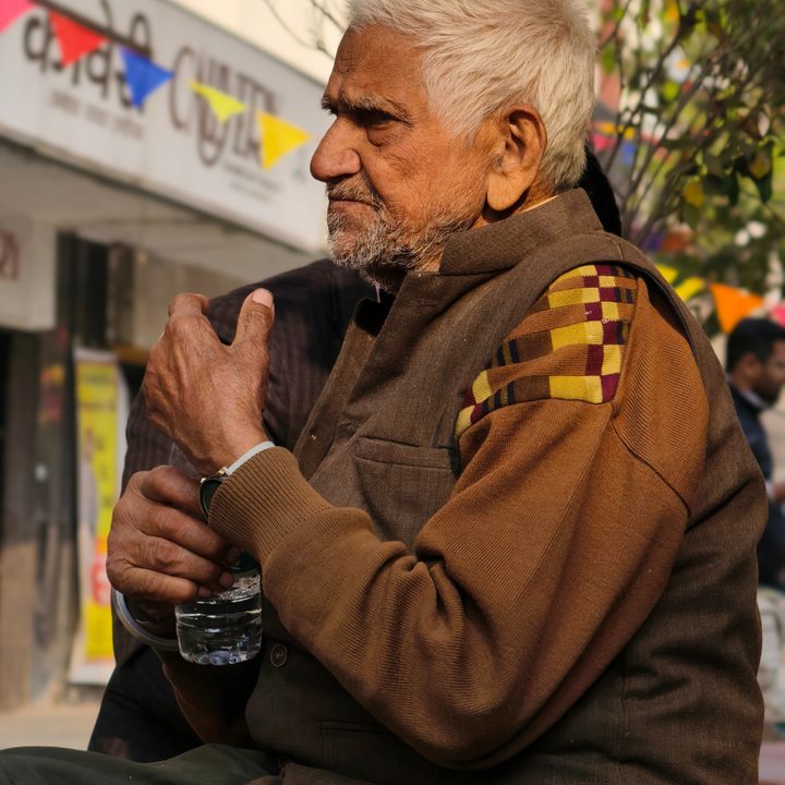 Old man holding sitting and a water bottle captured with the Vivo X200 Pro.