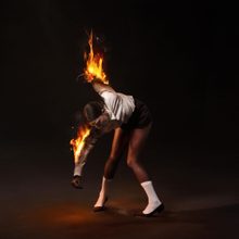 The artwork on the St. Vincent album All Born Screaming or a woman bent over with her arms on fire.