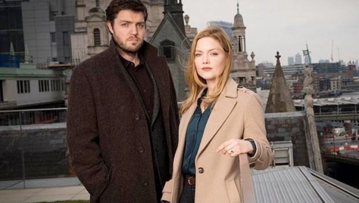 A man and a woman stand on a bridge in Strike.
