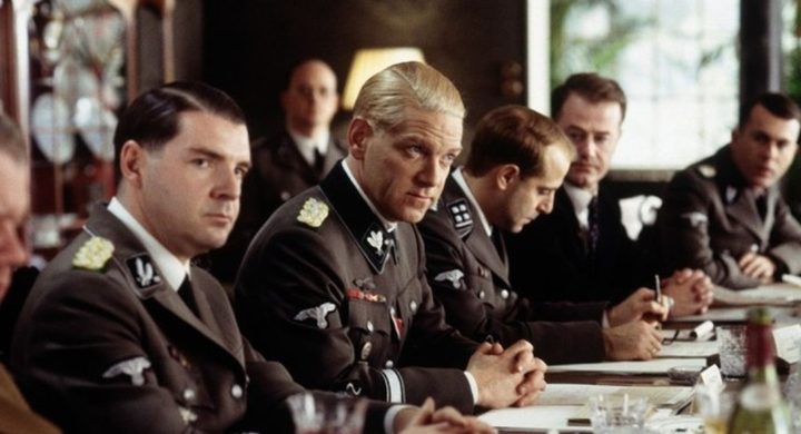 A group of men sit at a table in Conspiracy.