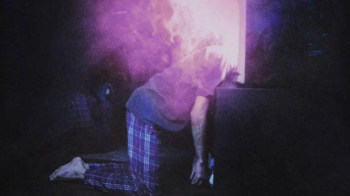 A man lays limp with his head in a TV set in I Saw the TV Glow.