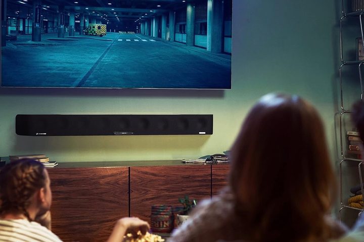 A family watching a TV with the Sennheiser Ambeo Max mounted below it.