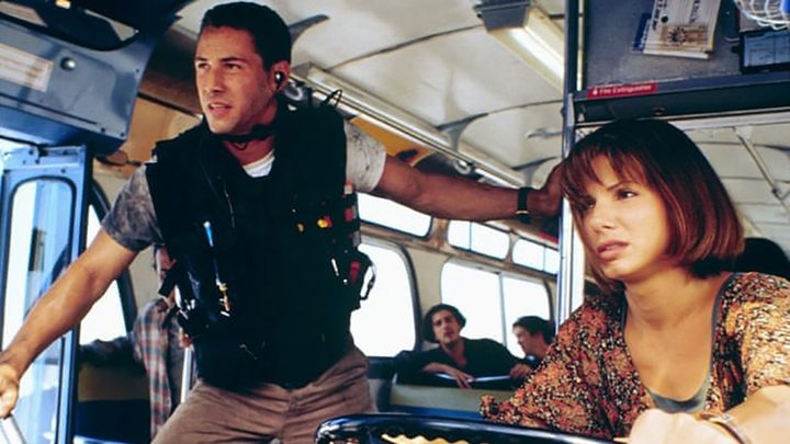 Keanu Reeves wearing a vest while Sandra Bullock rides a bus in Speed.