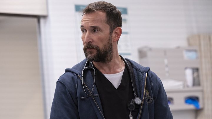 A doctor stands in his hoodie with a stethoscope around his neck looking to the left in The Pitt.