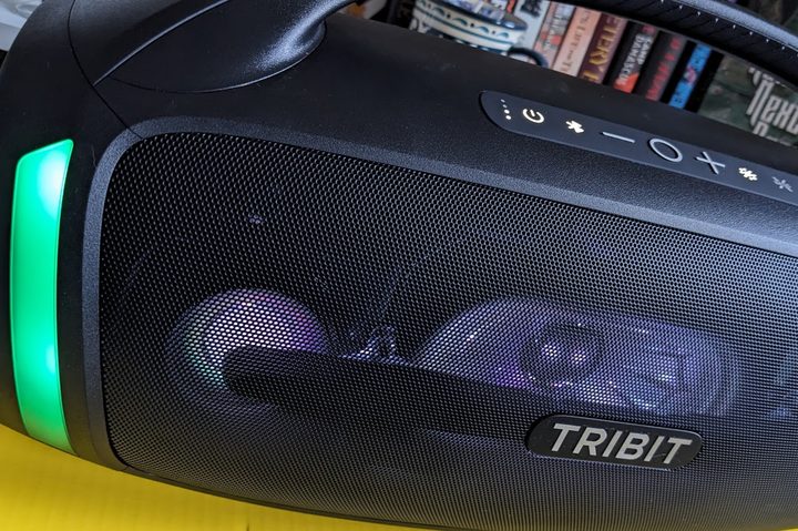 The Trbit StormBox Blast 2 bluetooth speaker, with its lightbars lit up green. The button array is visible on top of the speaker.