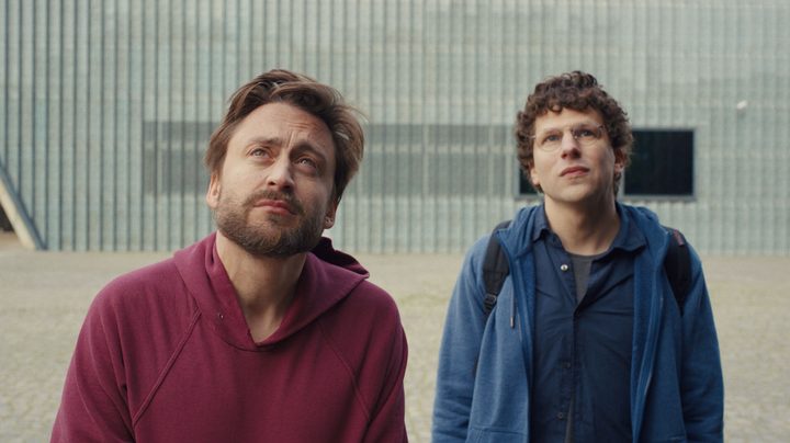 Kieran Culkin and Jesse Eisenberg stare at something in a still from the movie A Real Pain.