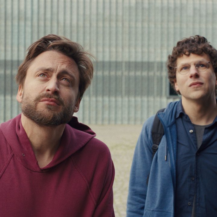 Kieran Culkin and Jesse Eisenberg stare at something in a still from the movie A Real Pain.