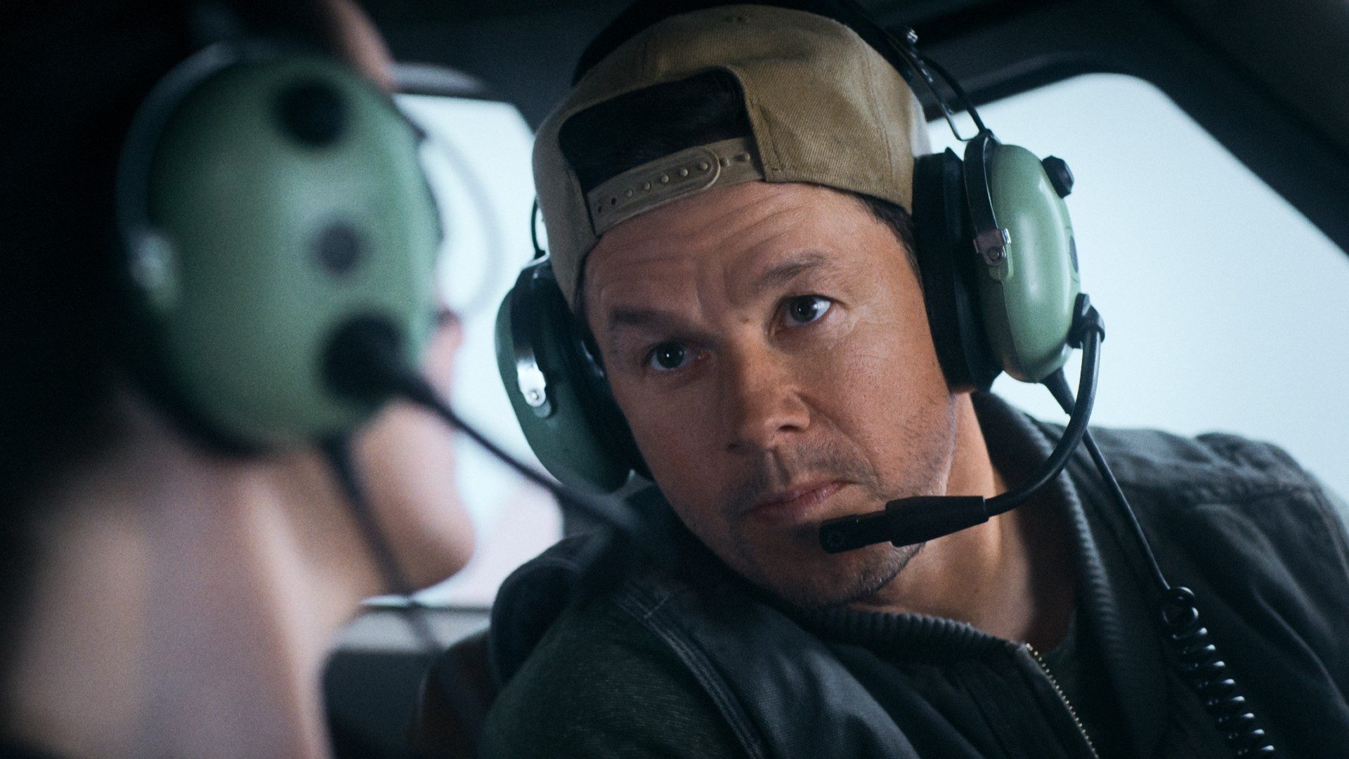Mark Wahlberg talks into an airplane headset in a still from the movie Flight Risk.