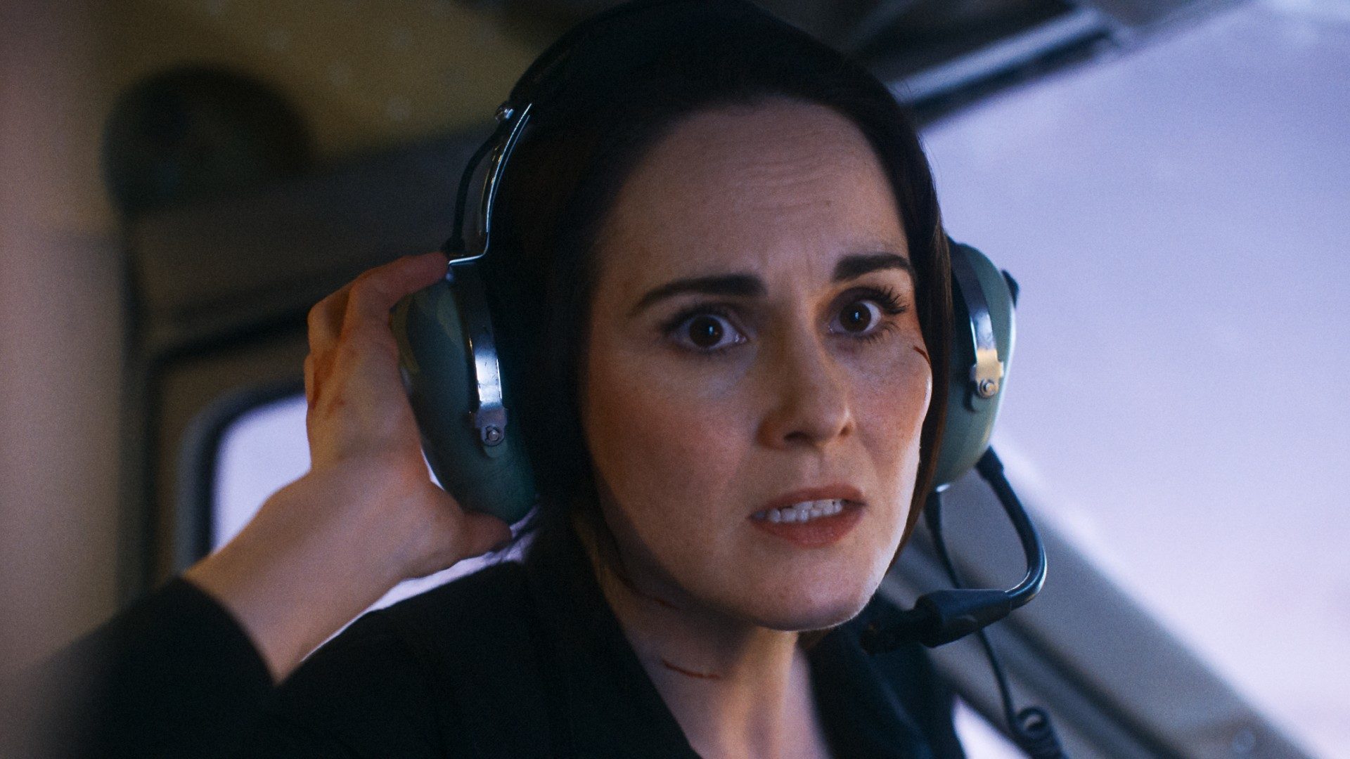 Michelle Dockery looks panicked with a airplane headset on in a still from the movie Flight Risk.