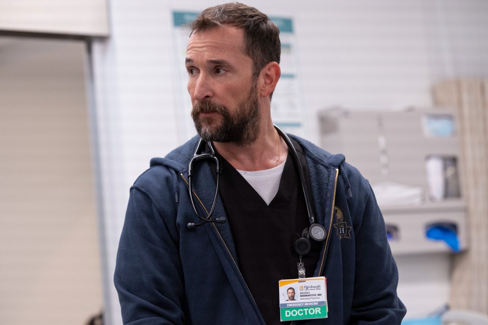 Noah Wyle wears a hoodie and hospital scrubs in The Pitt.