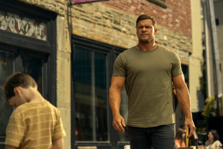 A huge man walks down the street in Reacher season 3.