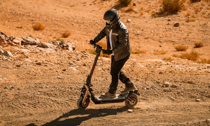 Rider wearing a helmet, leather jacket, and boots on a Segway GT3 Pro in the desert.